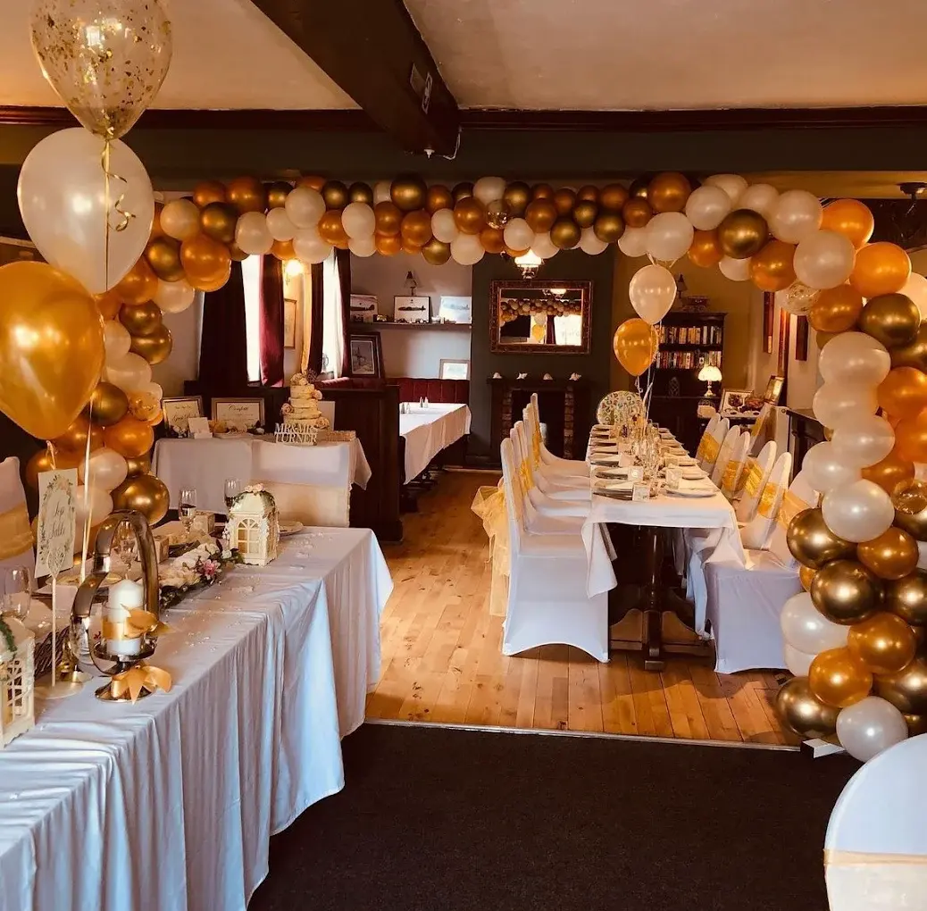 The dining room dressed for a celebration with a gold balloon arch