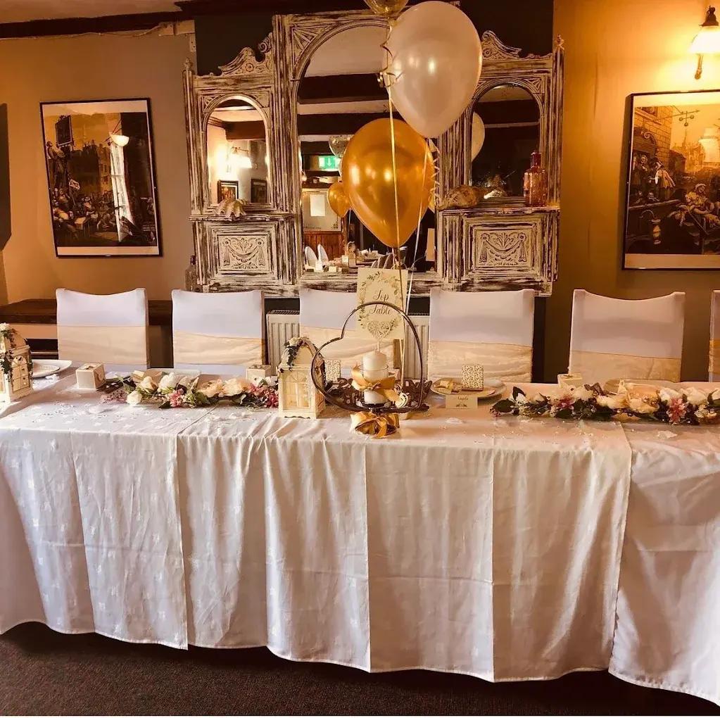 A dressed top table in the dining room, with flowers, balloons and gold sashes