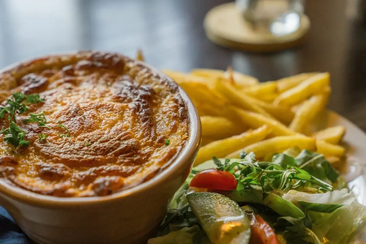 A golden-topped oven bake served with chips and salad